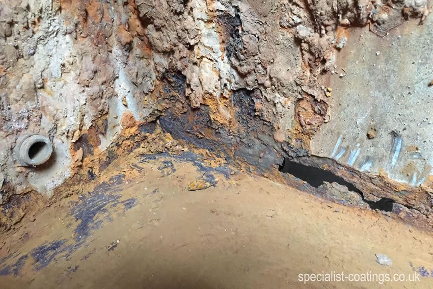 Rusty and leaking galvanised steel cold water tank. Before treatment with advanced corrosion and 30cm x 5cm hole. CWT Repair and lining service Specialist Coatings (GB) Ltd.